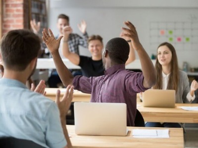 Menschen in einem Klassenzimmer feiern und applaudieren.